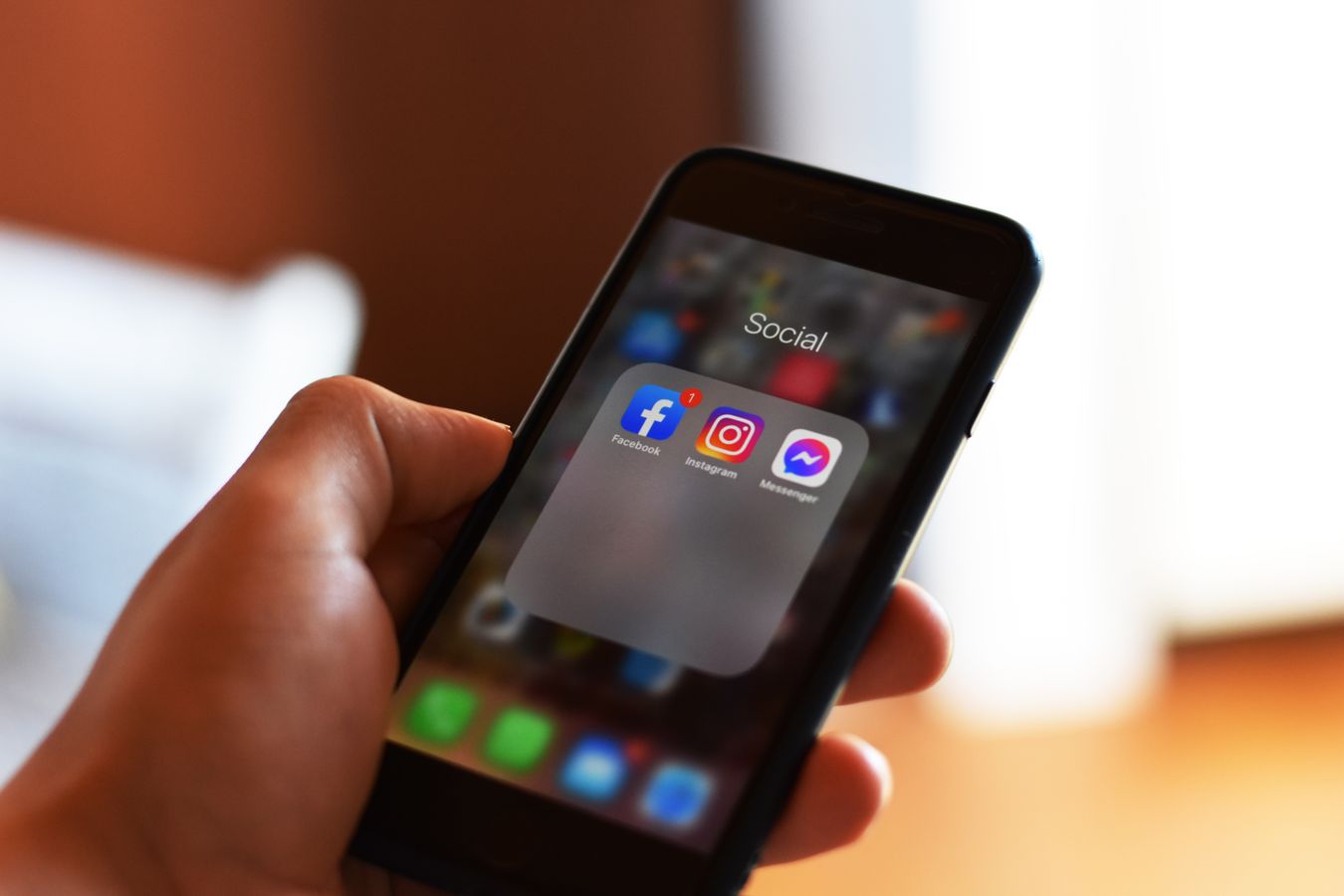 Mãos segurando celular com aplicativos de redes sociais como Instagram e Facebook