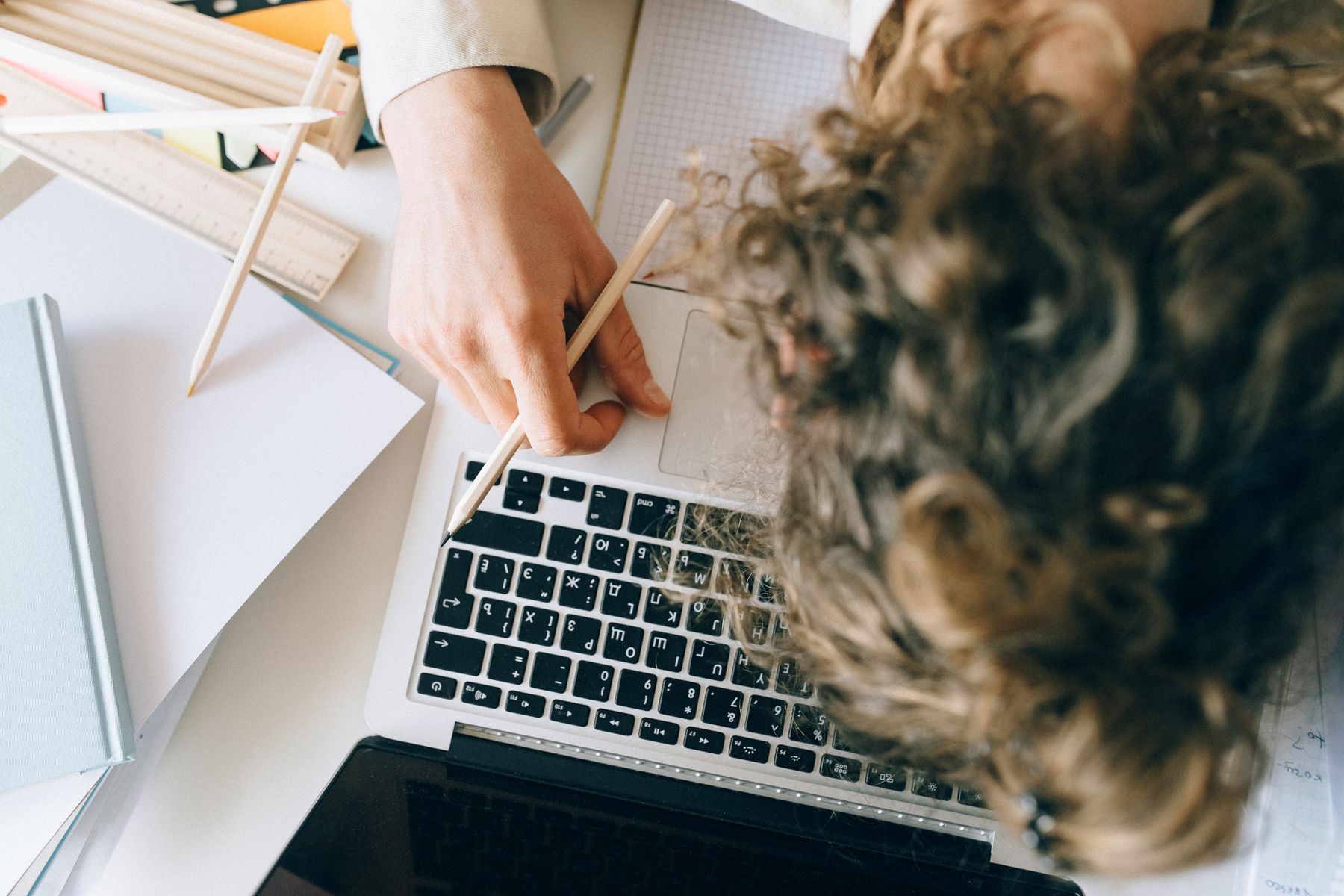 Funcionário exausto apoiado sobre notebook e papéis na mesa de trabalho