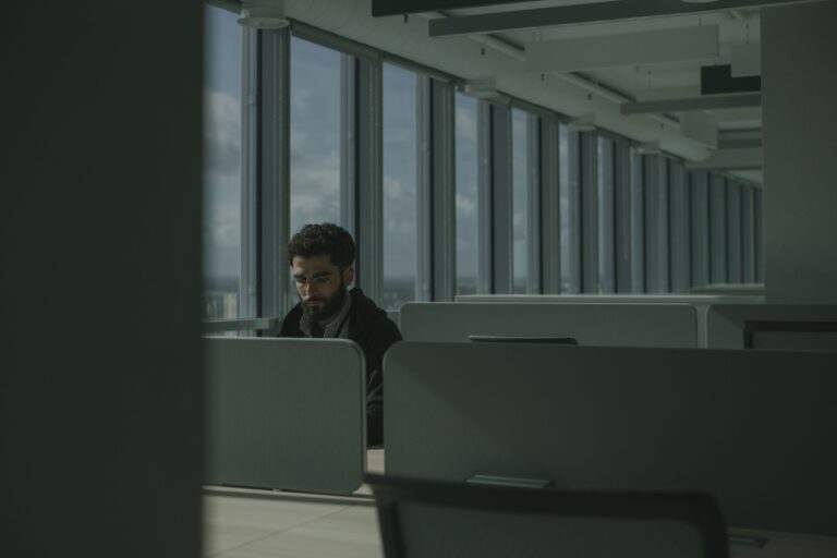 Homem trabalhando sozinho em escritório moderno, simbolizando isolamento no trabalho