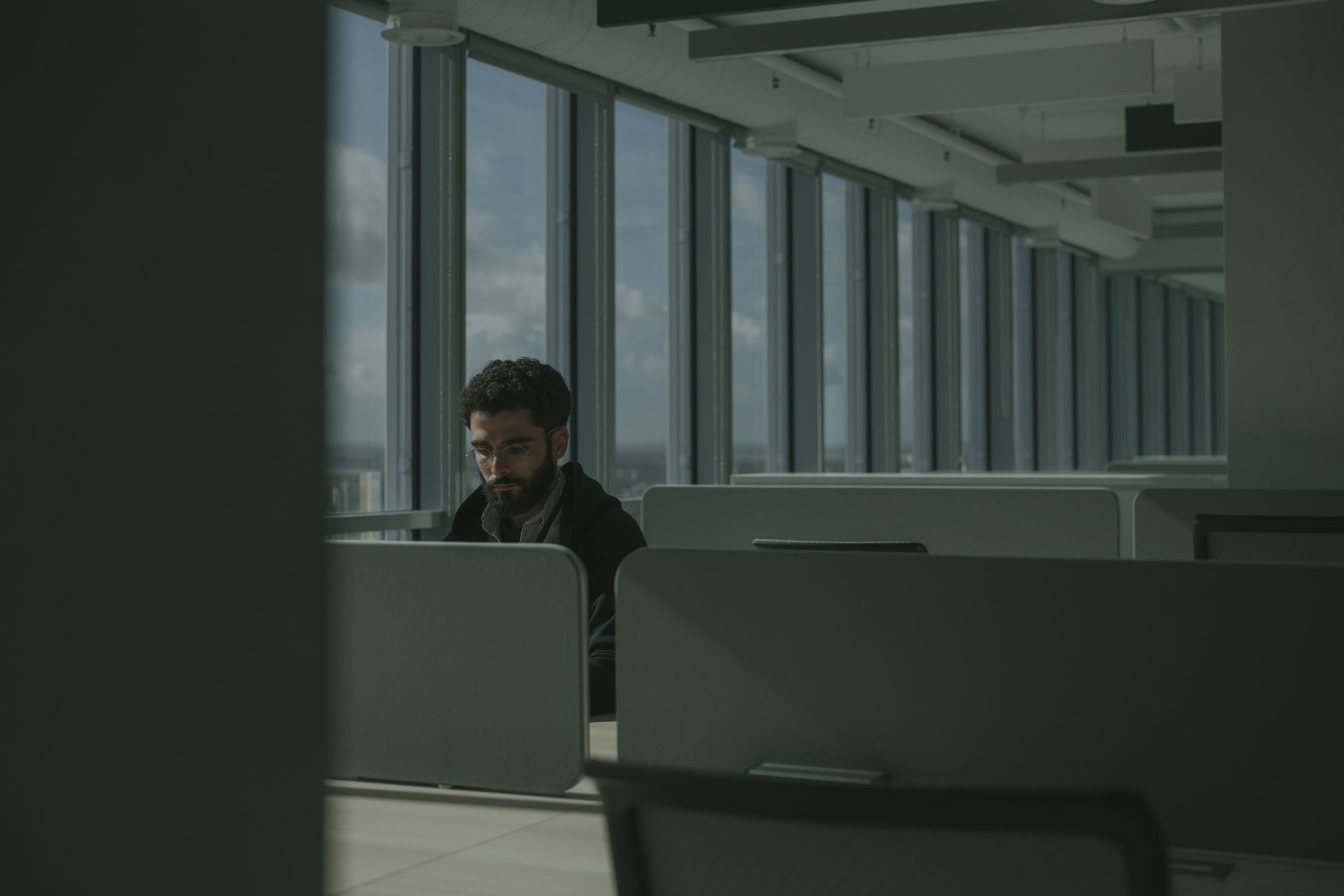 Homem trabalhando sozinho em escritório moderno, simbolizando isolamento no trabalho