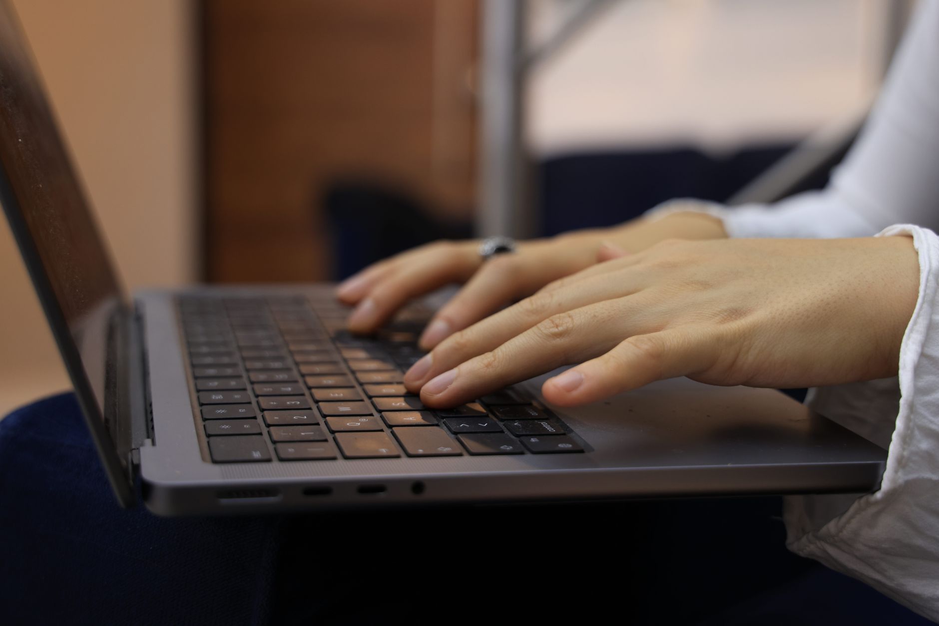 Close de mãos digitando em teclado de notebook durante trabalho remoto