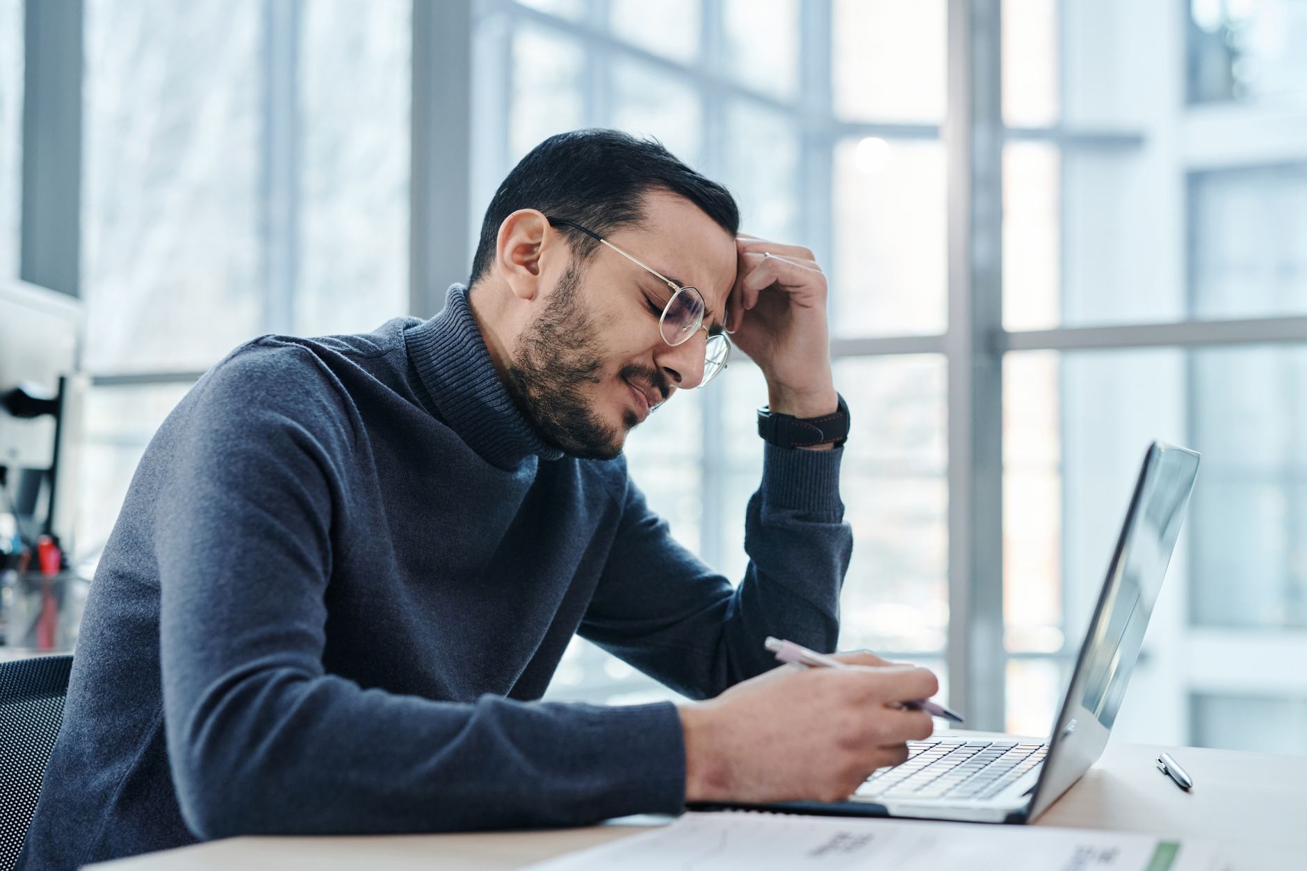 Homem parece estressado em frente ao computador em escritório