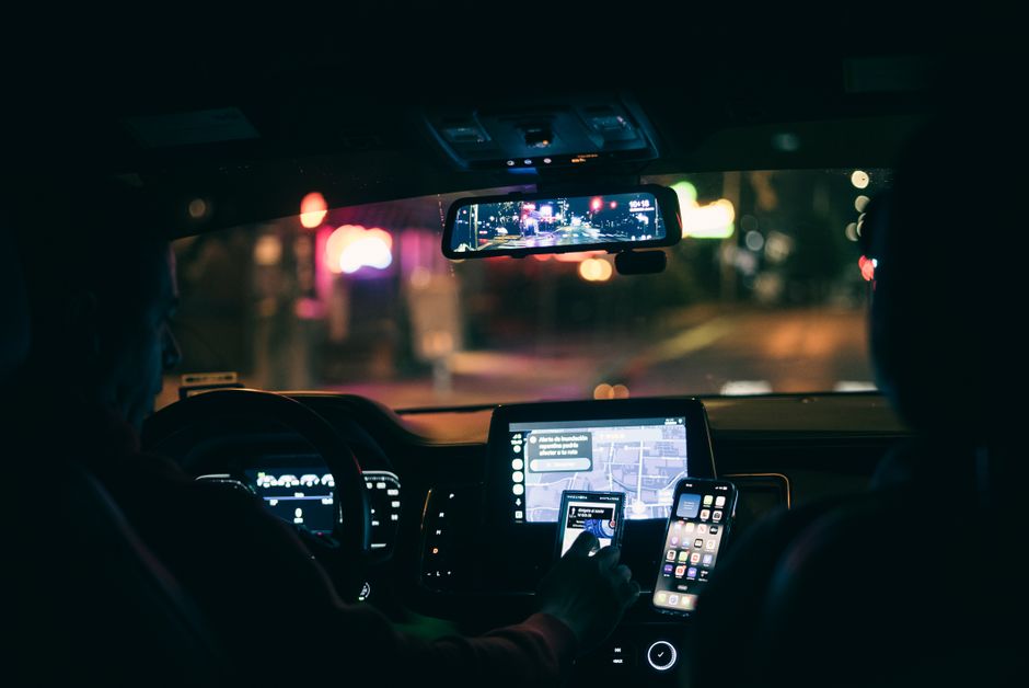 Motorista de aplicativo usando GPS no celular dentro do carro à noite