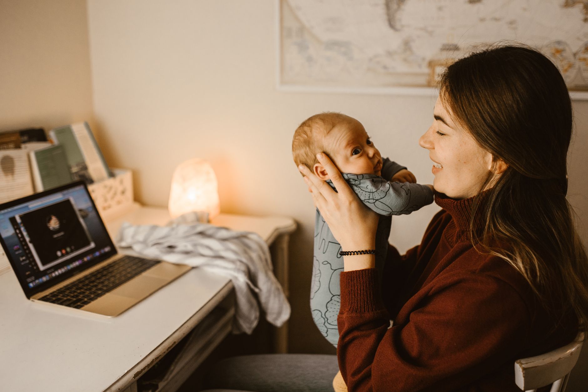 Mãe trabalhadora usando notebook em casa com bebê no colo
