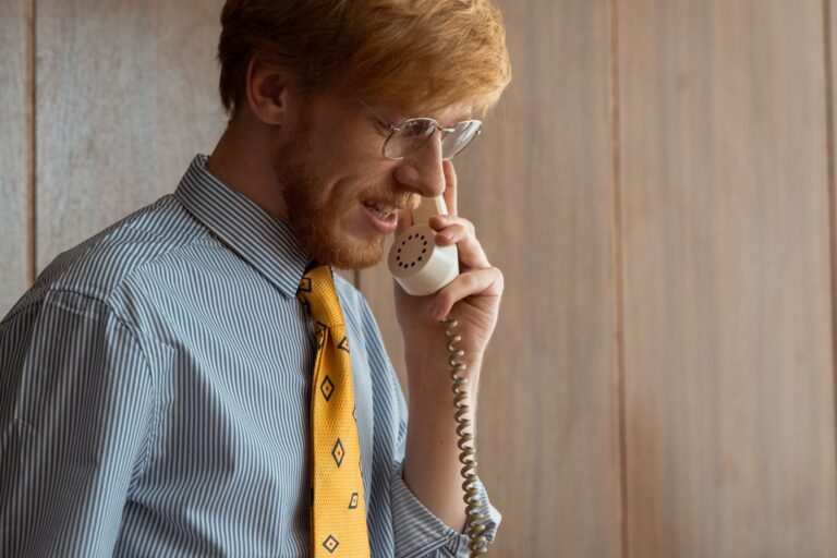 Homem de barba fala ao telefone em ambiente de escritório