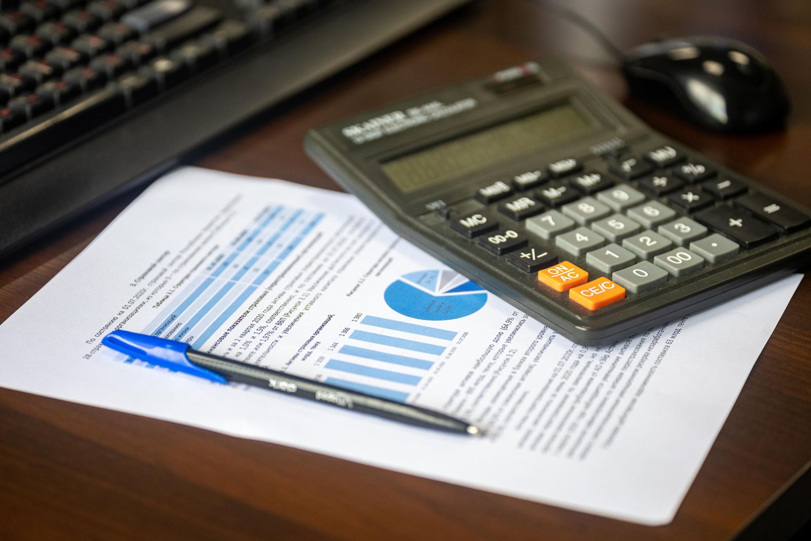 Pessoa usando calculadora com documentos financeiros sobre a mesa