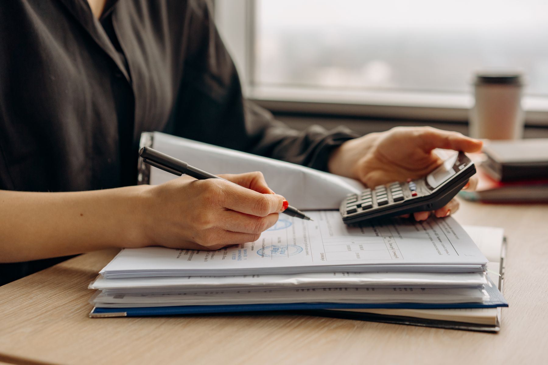 Pessoa utilizando calculadora com documentos financeiros