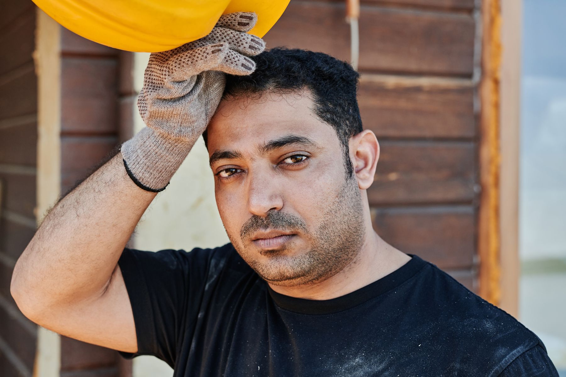 Trabalhador da construção civil exausto segurando capacete de proteção