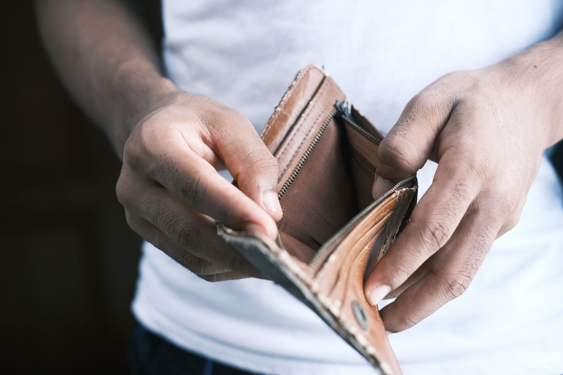 Mãos segurando carteira vazia, representando dificuldade financeira após demissão sem receber a rescisão