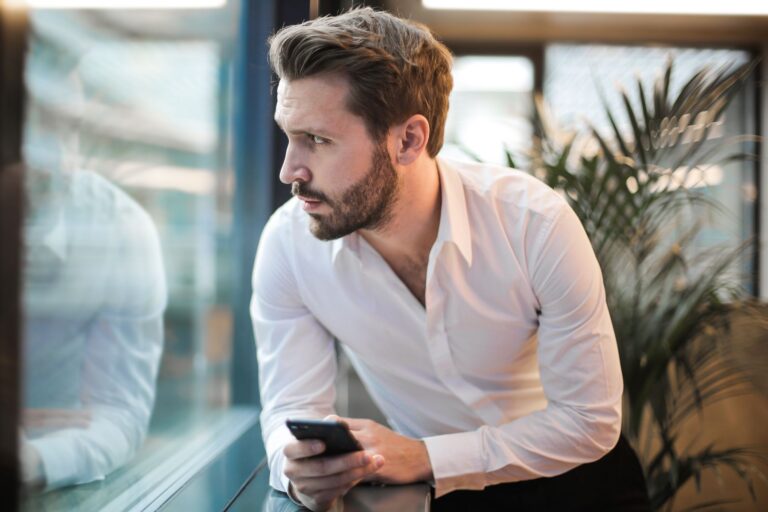 Homem em ambiente de trabalho olhando preocupado para o celular