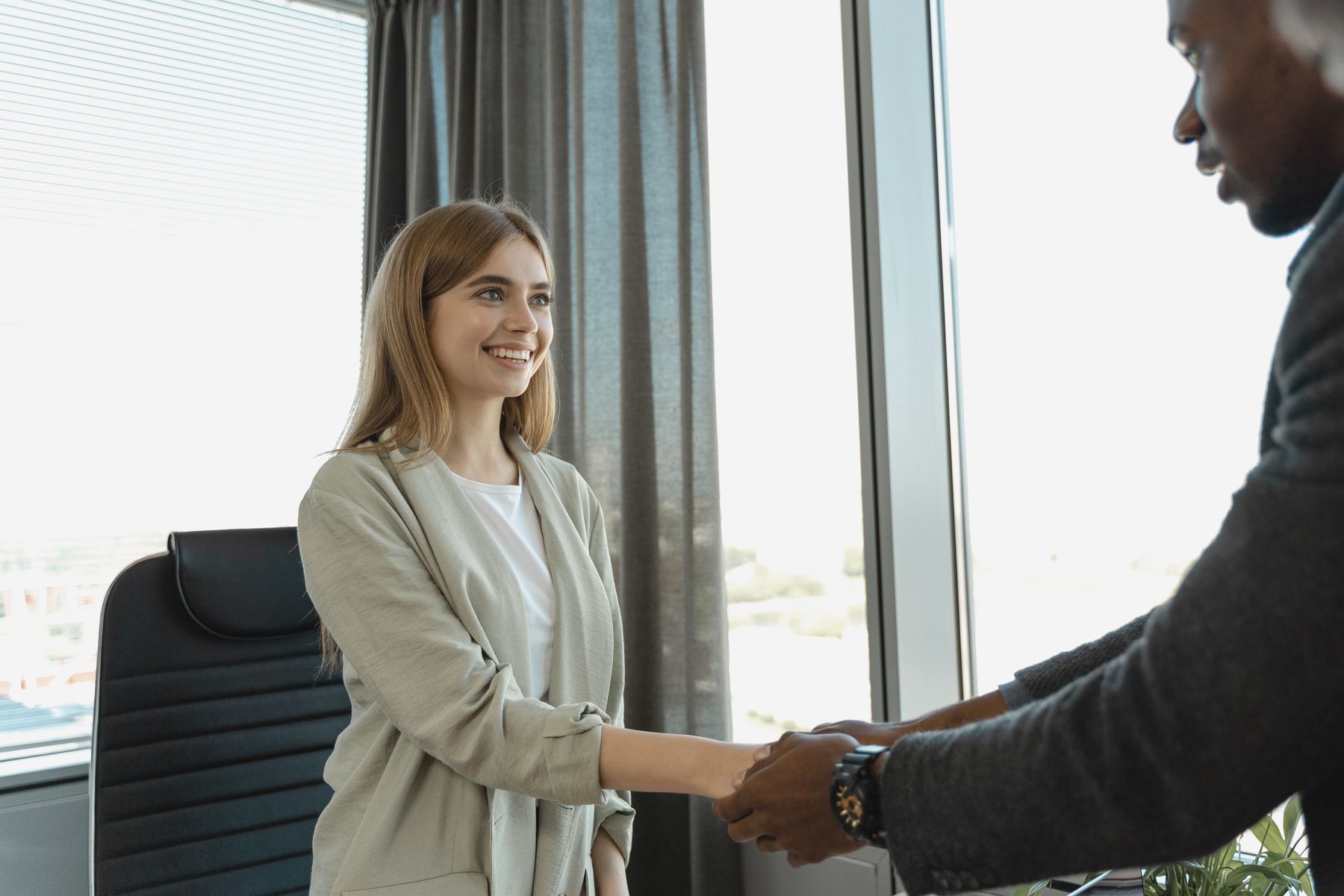 Entrevista de emprego com aperto de mãos entre candidata e recrutadora, novo emprego CLT durante o seguro-desemprego