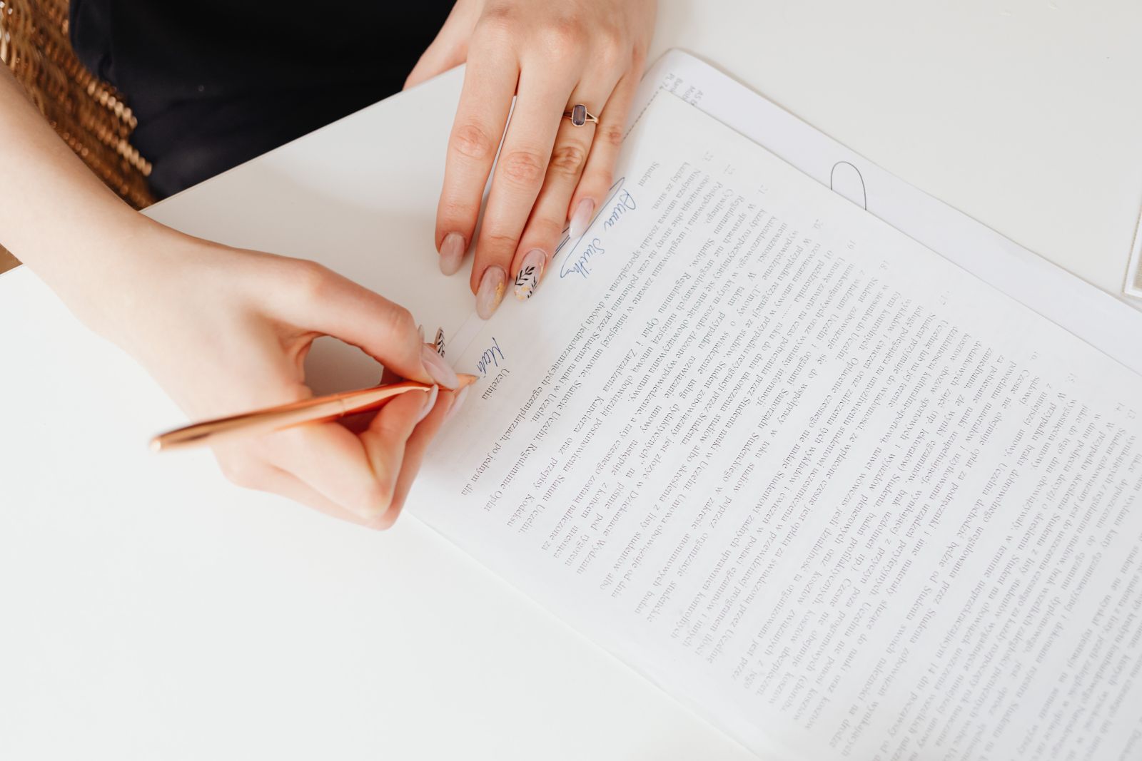 Close das mãos de uma mulher assinando um documento
