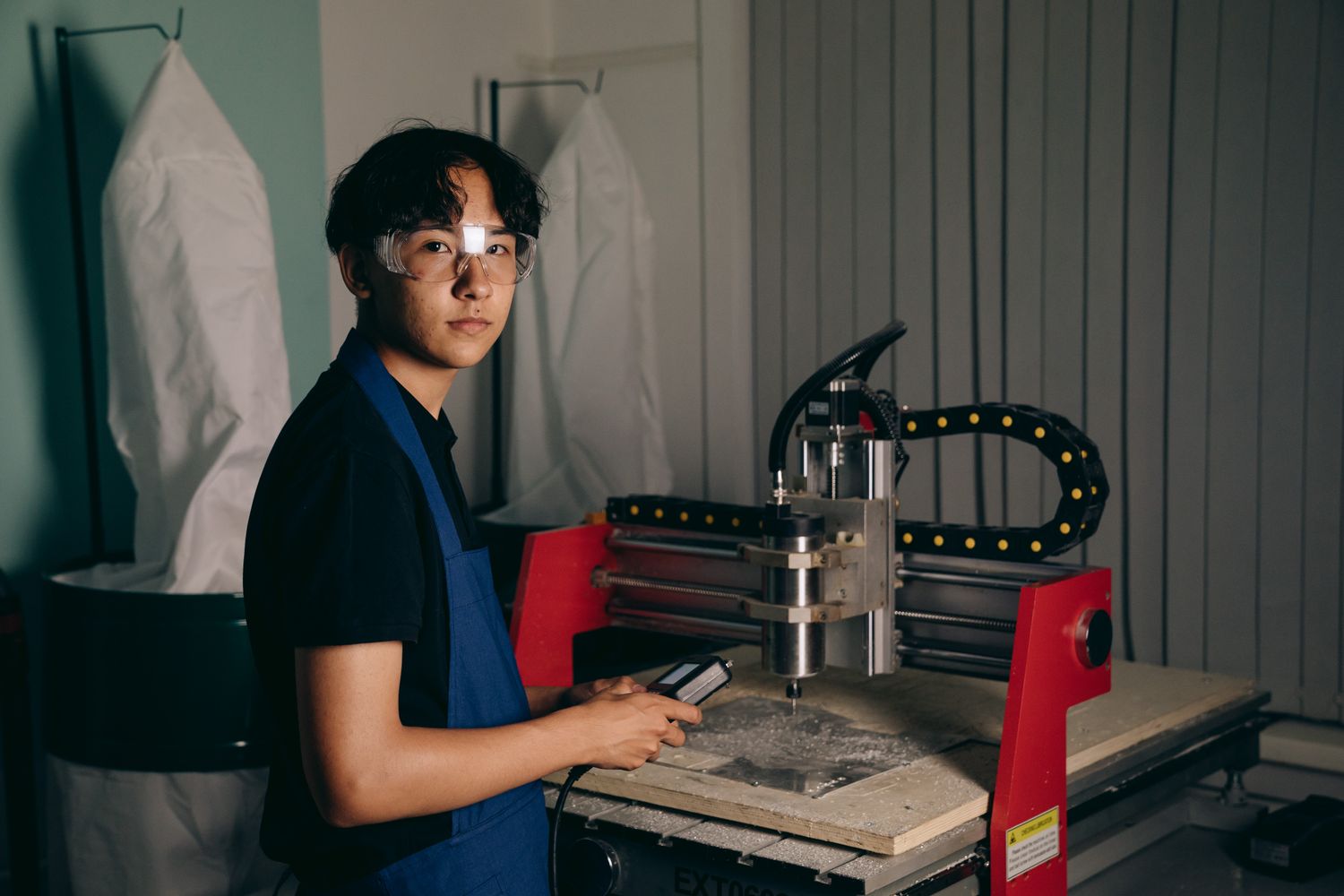 Jovem aprendiz operando máquina em oficina