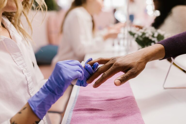 Manicure aplicando esmalte nas unhas de cliente em salão de beleza
