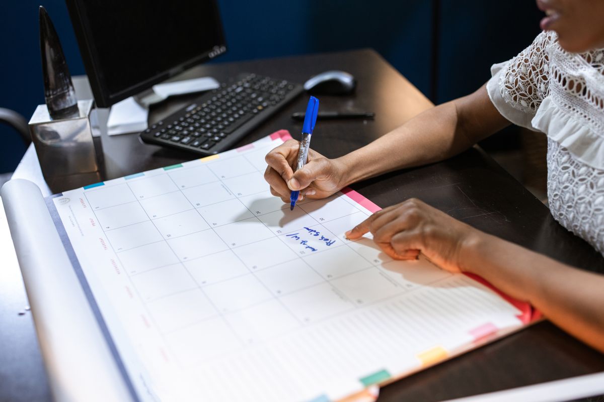 Pessoa anotando datas em um calendário de mesa
