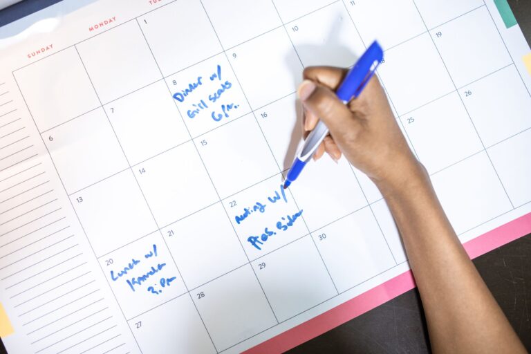 Pessoa anotando compromissos e horários em um calendário de mesa