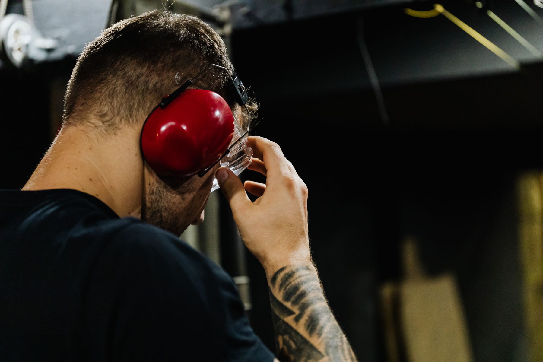 Trabalhador ajustando protetor auricular e óculos de proteção em ambiente industrial