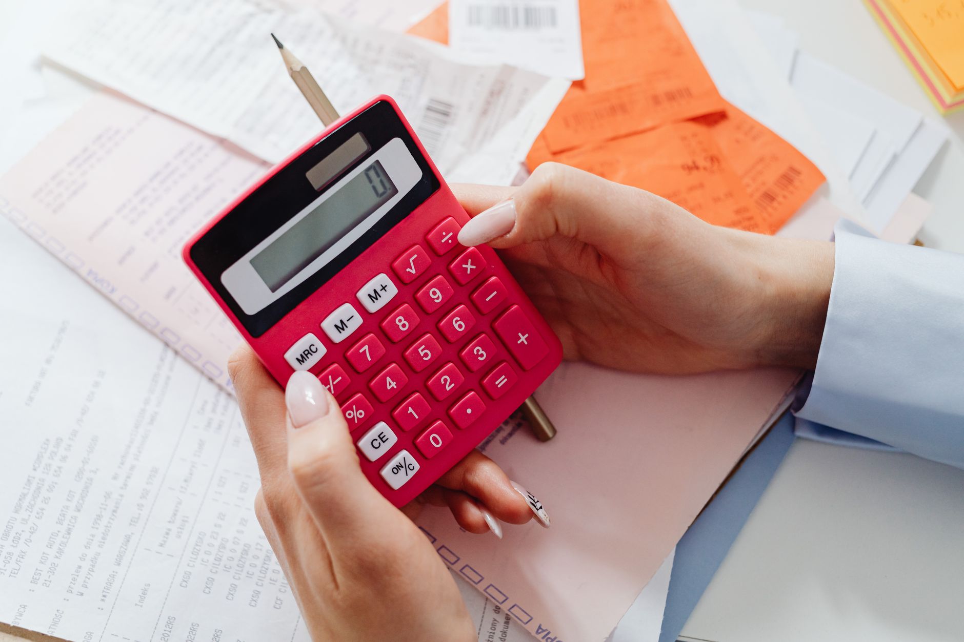 Mãos segurando uma calculadora sobre documentos para calcular férias proporcionais
