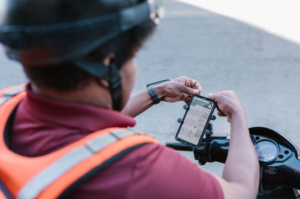 Entregador de aplicativo consultando o celular sobre a moto