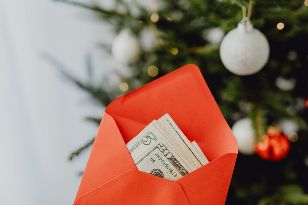 Envelope vermelho com dinheiro diante de árvore de Natal