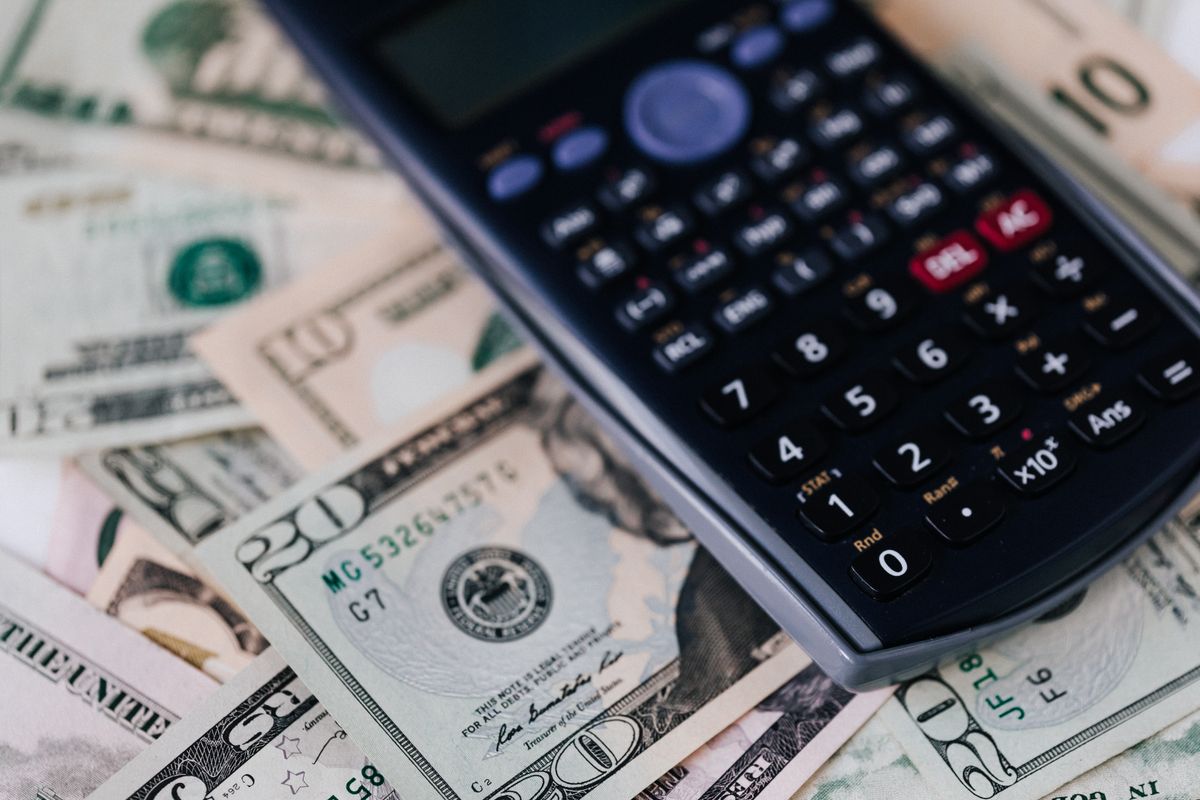 Calculadora e dinheiro sobre uma mesa, vistos de cima