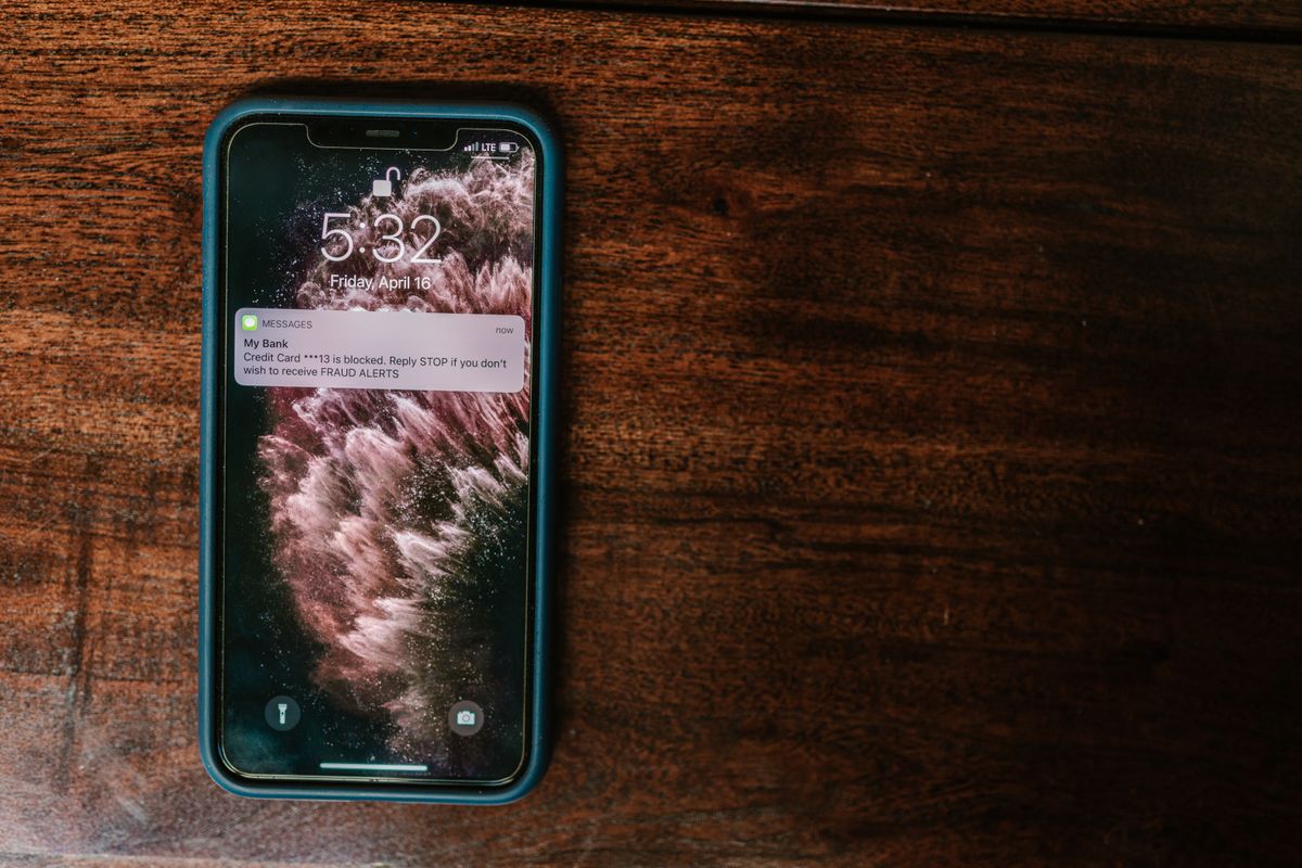 Celular sobre mesa de madeira exibindo um alerta do banco