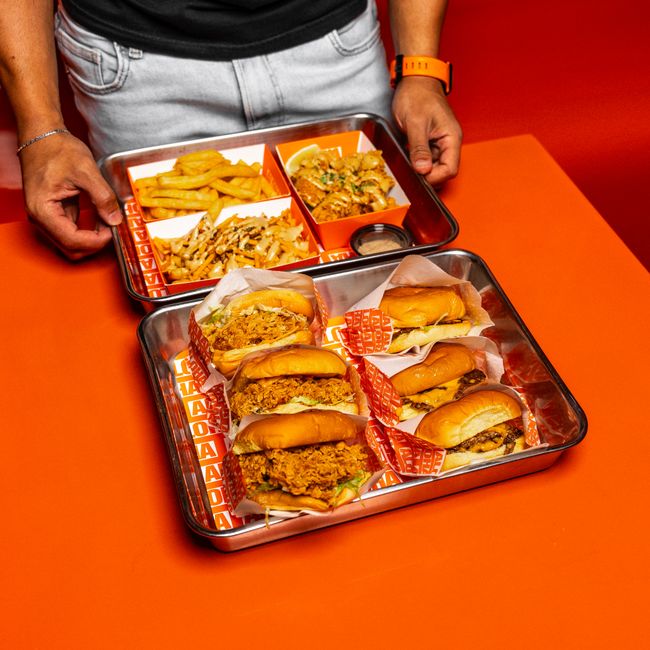 Hambúrgueres e batatas fritas servidos em bandejas