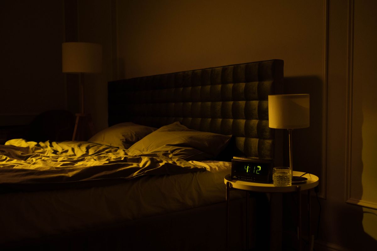 Quarto com despertador digital marcando 4h12 da madrugada