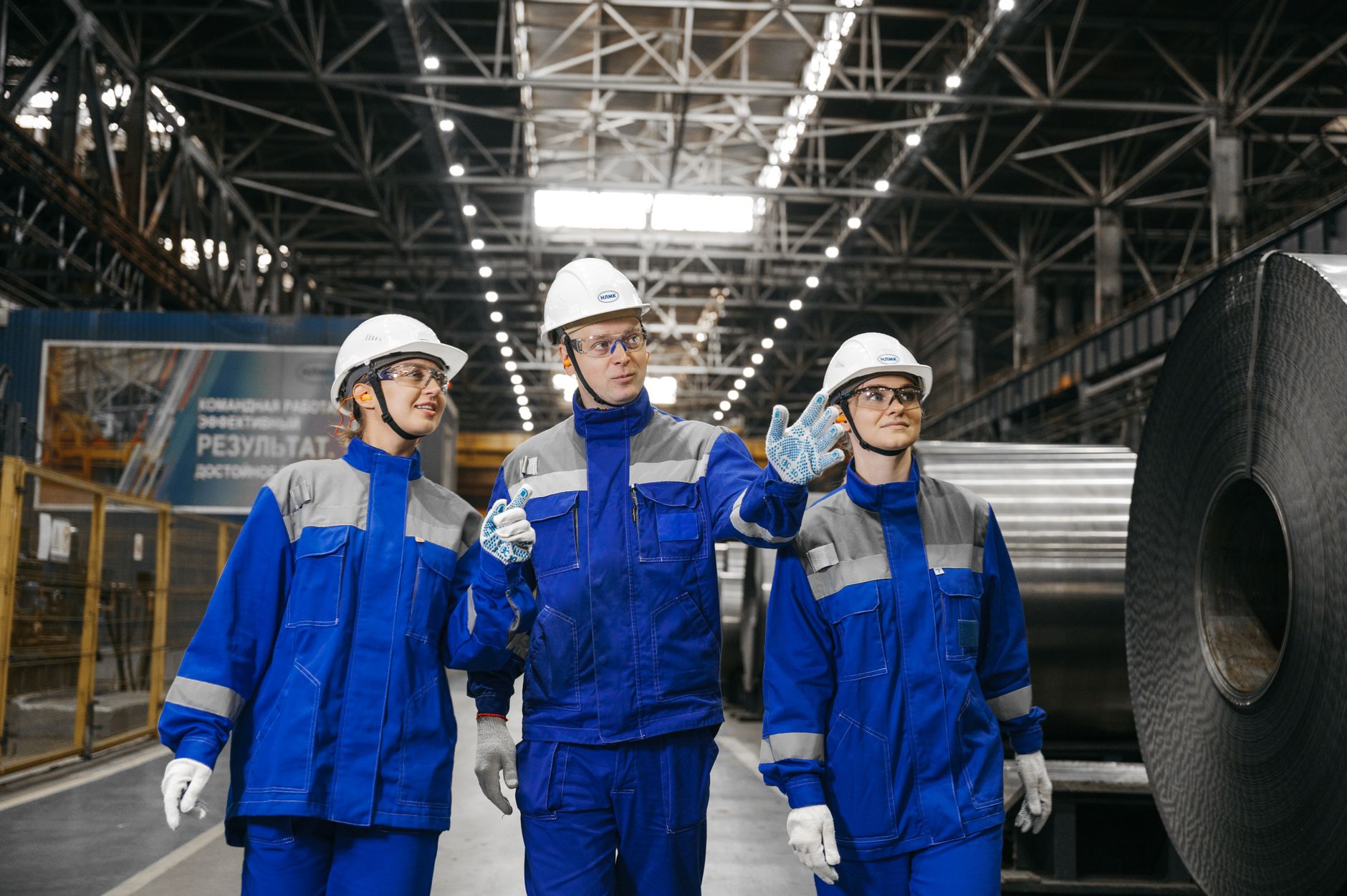 Trabalhadores de uniforme e equipamentos de segurança dentro de uma fábrica