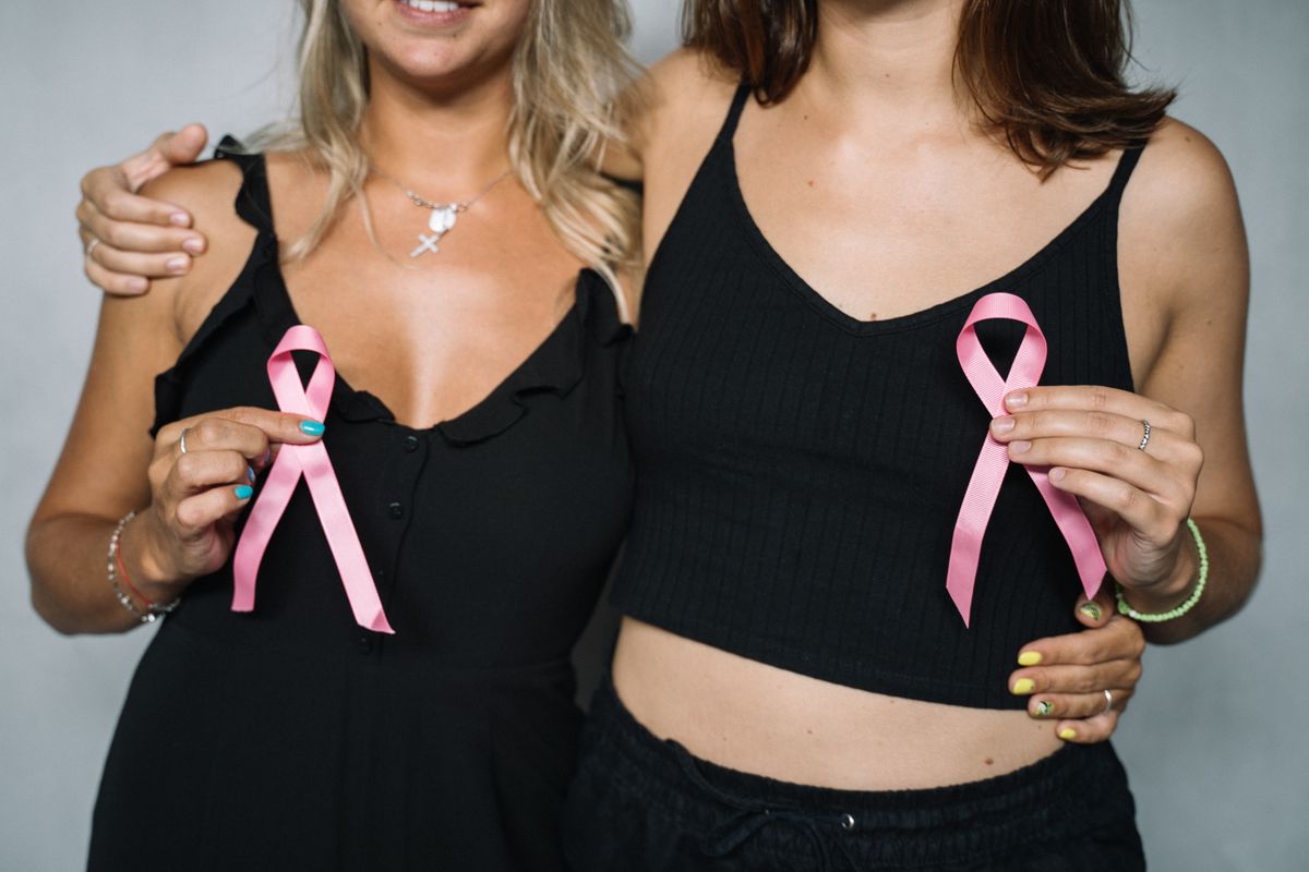 Duas mulheres segurando laço rosa em apoio à campanha contra o câncer de mama
