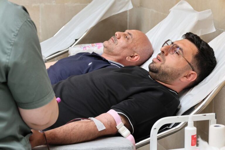 Dois homens deitados em macas doando sangue em um hospital