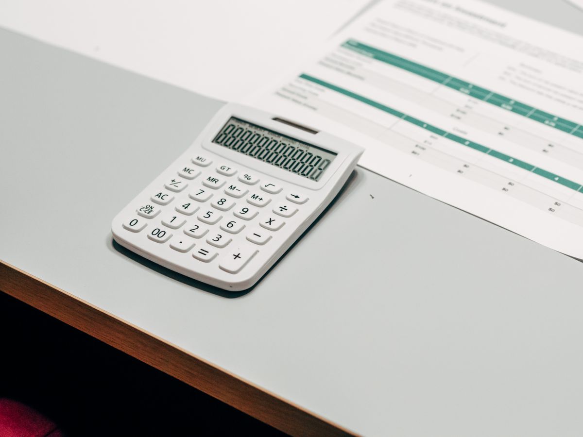 Calculadora ao lado de planilha financeira sobre mesa de trabalho
