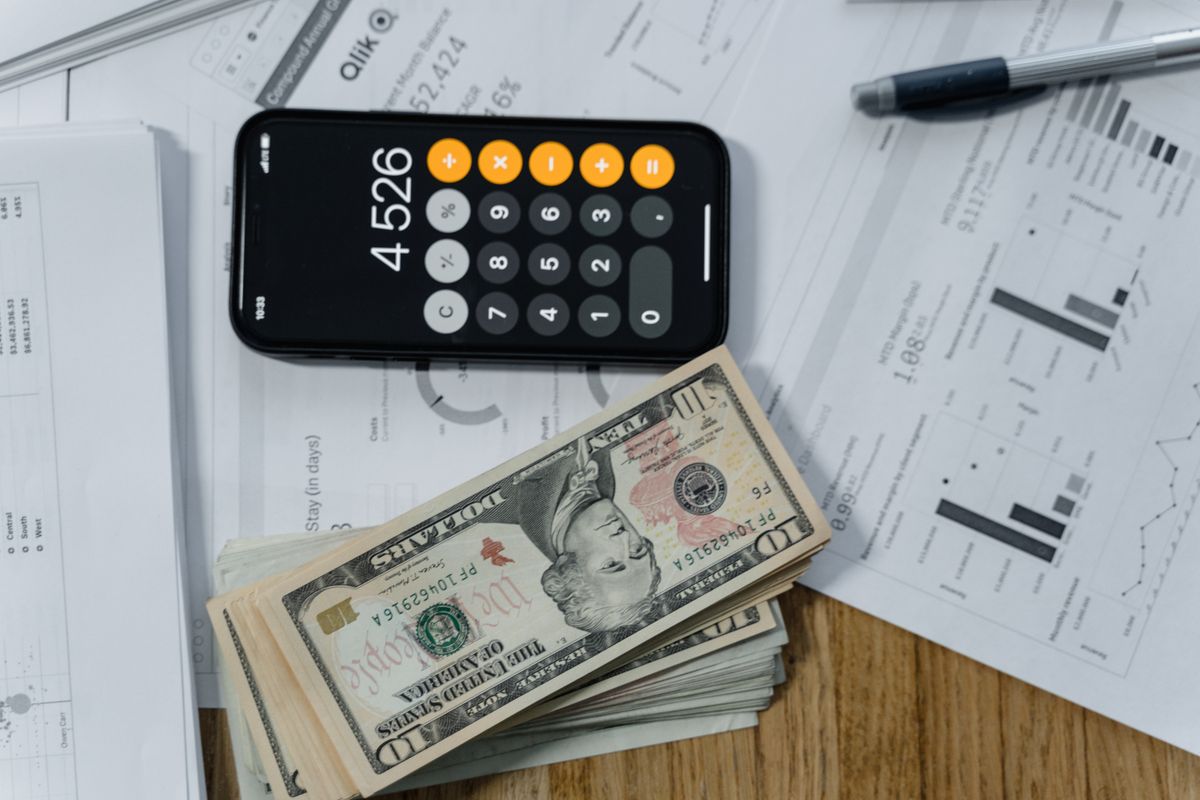 Calculadora, dinheiro e documentos financeiros sobre uma mesa