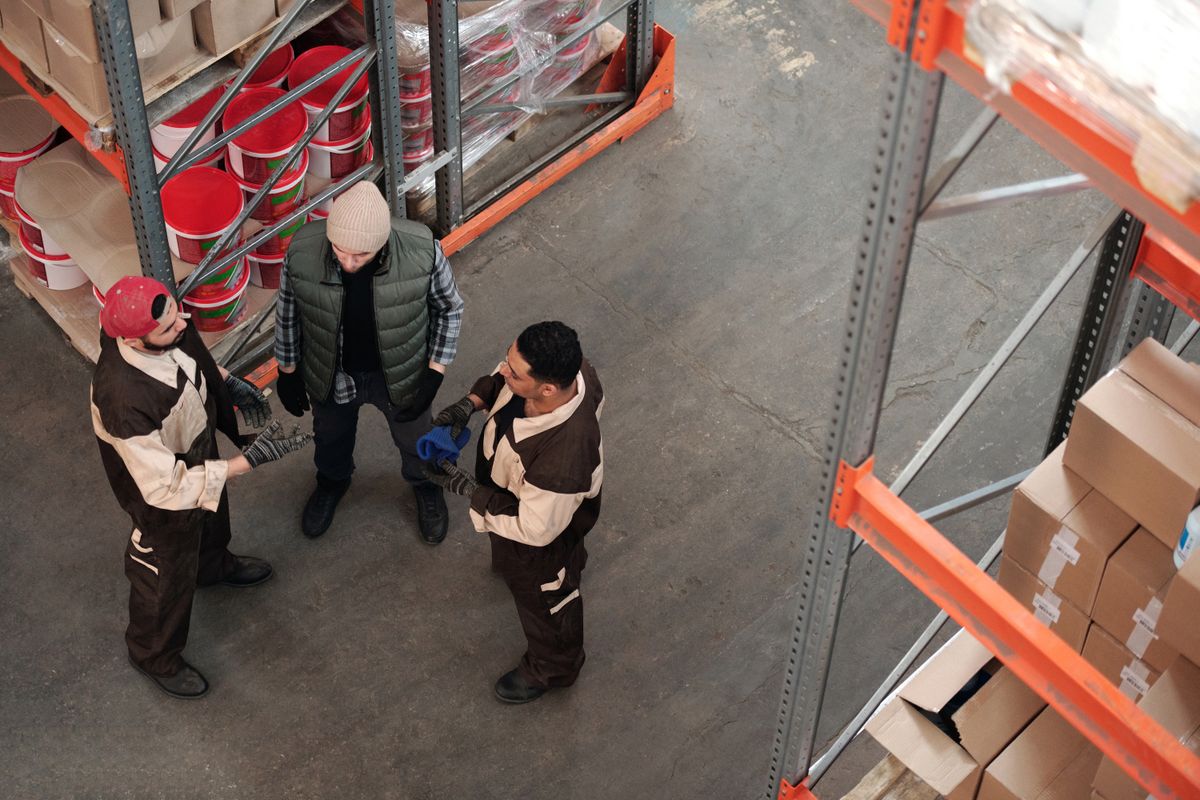 Três trabalhadores conversando em um galpão industrial