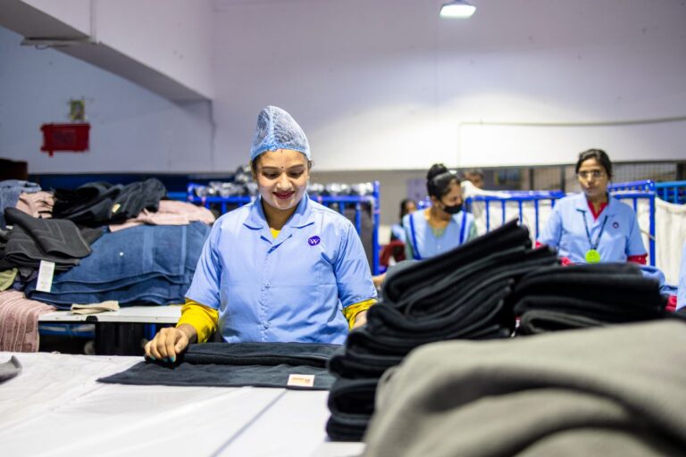 Trabalhadoras de uniforme azul em linha de produção de fábrica