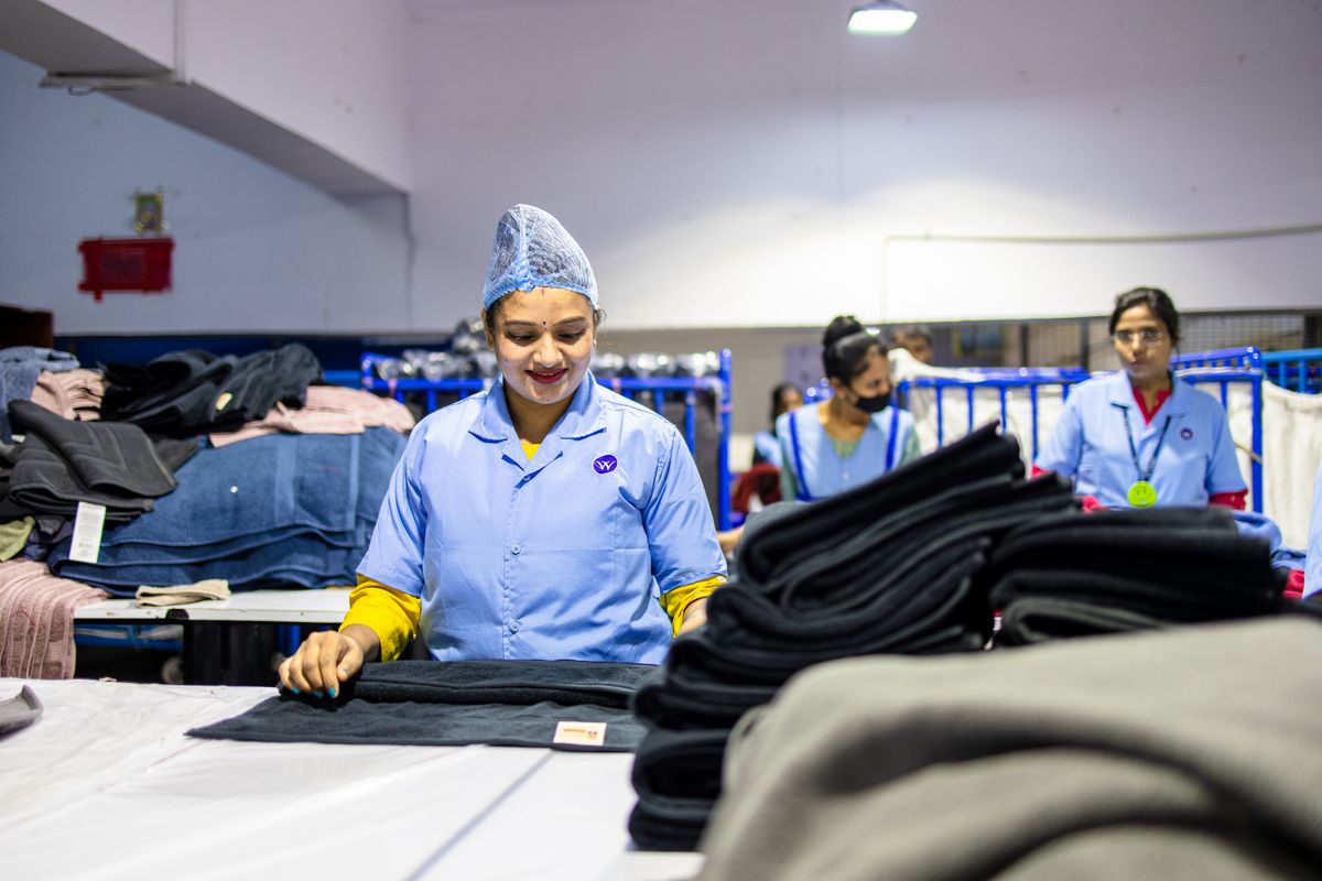 Trabalhadoras de uniforme azul em linha de produção de fábrica